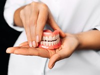 a dentist holding dentures in her hands