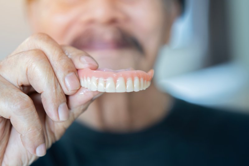 Patient holding u[ dentures using denture adhesive