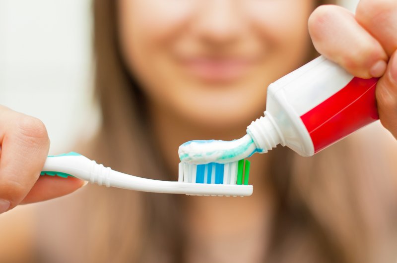 A woman applying toothpaste to her toothbrush 